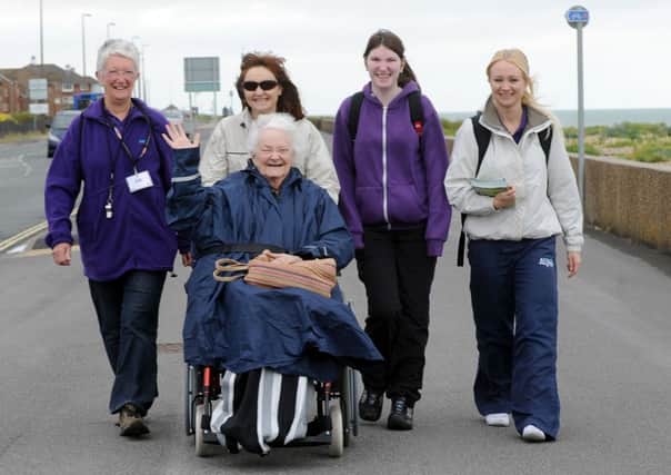Julia Dendle pushes Beatrice Collins in her wheelchair, with other walkers