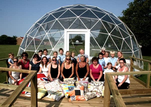 Leaders of the cushion-making project Kira Jones (back row, first right) and Lauren Willard (front row, five from the left) are pictured outside the dome with pupils, parents and staff.