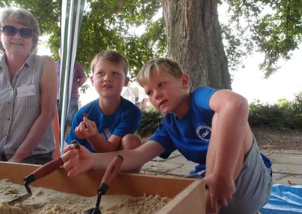 Brothers Oliver (left), six and Matthew Goff, nine, go digging, watched by museum volunteer Jan Eldred