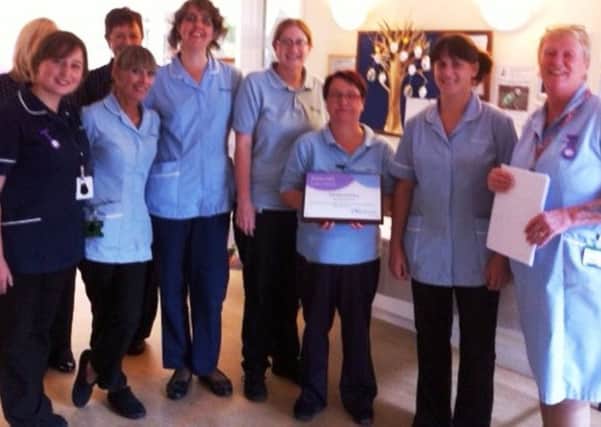 Elmcroft staff with the plaque presented by Suzanne Hughes