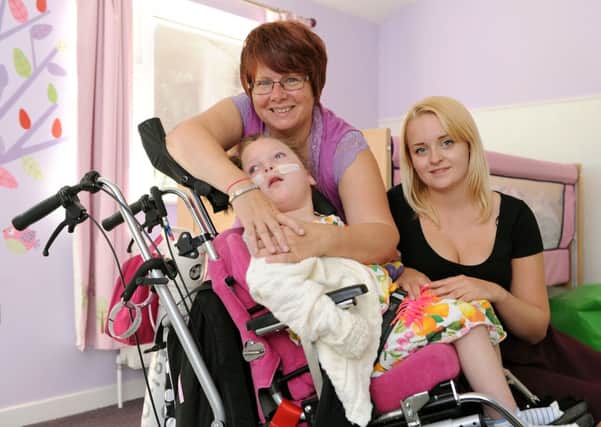 Andrea Thorne hugs her granddaughter Iona-May following the completion of the youngster's new room. Pictured with Iona-May's carer Katie Brewster                         L36222H13