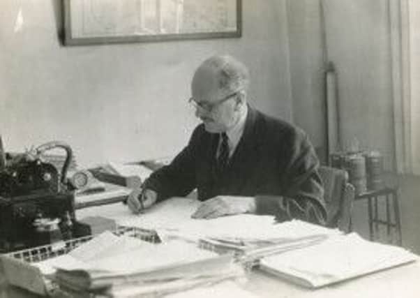 A photograph of Percy Cox working at his desk, from his archive.