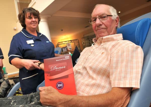 Geoffrey Spencer about to donate his 100th pint of blood under the supervision of Jenny Howlett, a donor care supervisor.