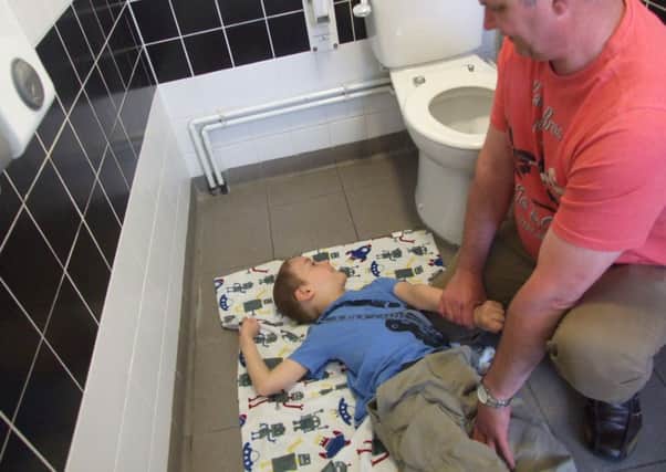Andrew Buck changing his son Alfie on the toilet floor
