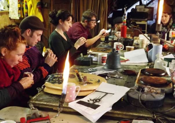 Students working with flames, which are used to heat the tools and melt wax. The wax model for a ships bell is in the centre, awaiting inscription. PICTURE: MIKE WOOLDRIDGE