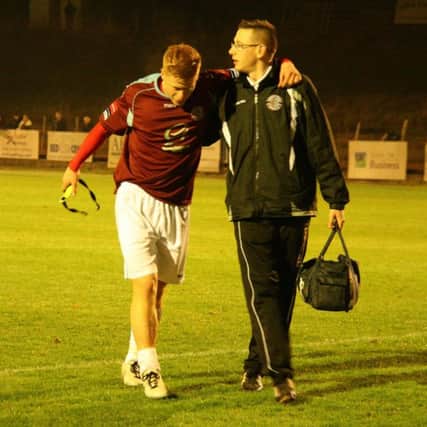 Hastings United striker Trevor McCreadie is helped off by physio Dane Martin