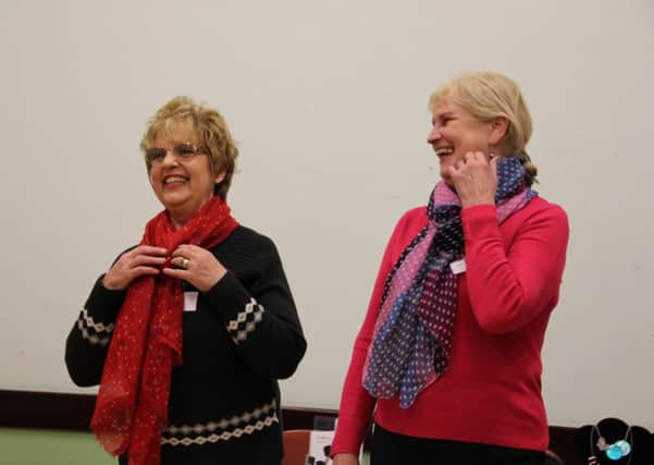 Sue Moody and Jan Lucas of BHMWI trying scarves of varying colours and designs to see what suits
