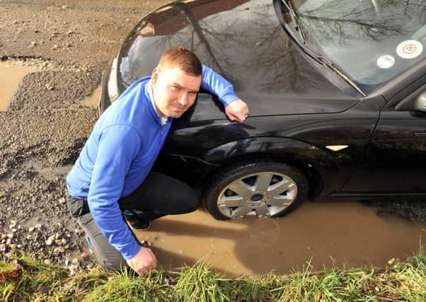 W06272H14 Aaron Squires and his car by a pothole near Hill Barn Golf Club