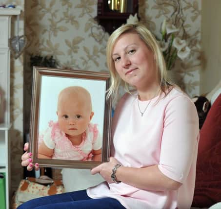 Jodie Dunk, pictured with a photo of her daughter, Mariah, who died of meningitis