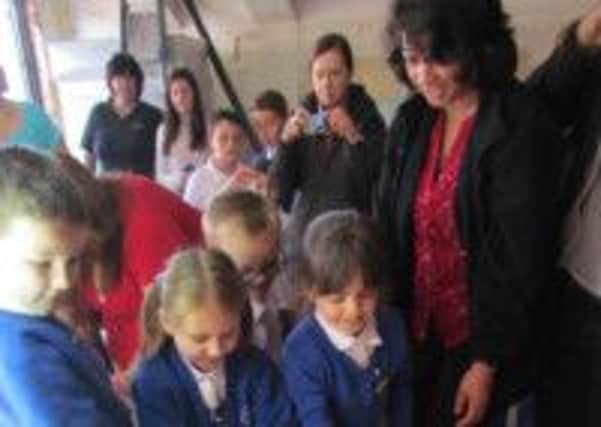 Nim Shingadia is pictured with children from Castlewood and members of the community placing the time capsule in the cellar SUS-140704-122158001