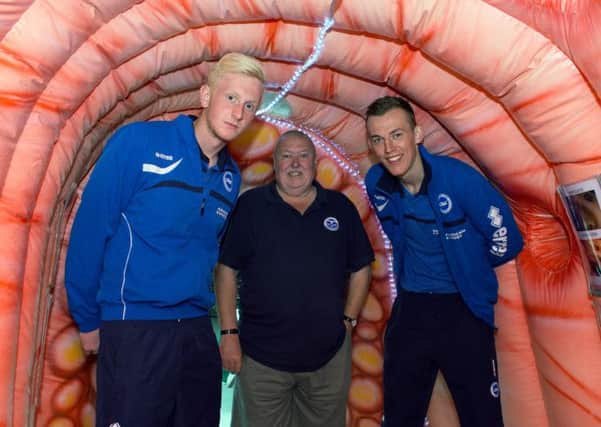 Albion players Josh Smith (left) and Christian Walton with bowel cancer survivor Charles Cushing inside the inflatable colon