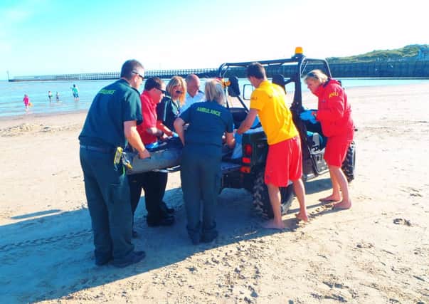 Littlehampton lifeguards and paramedics help an injured woman PHOTO: RNLI