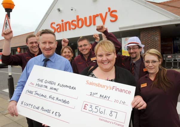 WH 210514 Sainsbury's store manager Paul Humphries presents Hollie Lucas, from the Queen Alexandra Hospital Home, a cheque