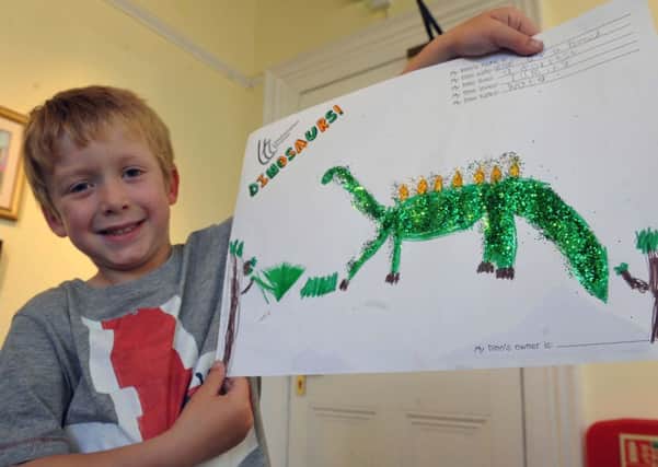 Ethan Boswell  showing off his piece of dinosaur art on Thursday            L22554H14 Dinosaur Workshop at Littlehampton Museum on Thursday  Ethan Boswell