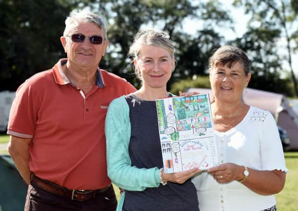 Deborah Chase (centre) is pictured showing the poster designed by her niece, Charlie Matheson, to Les and Jean Rutherford, the owners of Daisyfields Touring Park                                                                           PHOTO: Liz Pearce