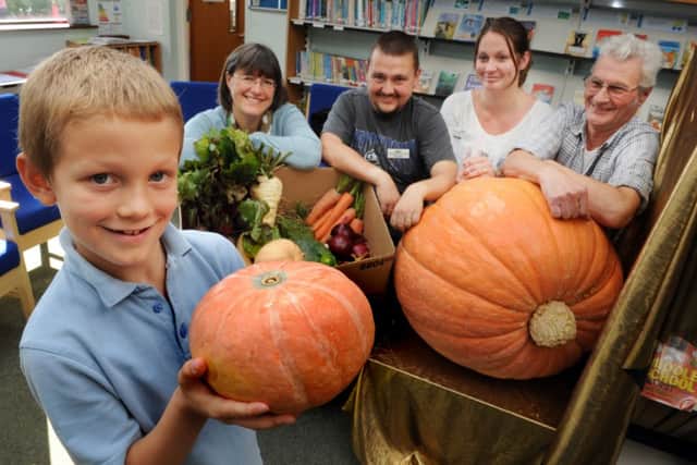 JPCT 071014 S14420547x Horsham. Northholmes school. Nathan, watched by teacher and family, holds a small pumpkin with the giant one behind -photo by Steve Cobb SUS-140710-143544001