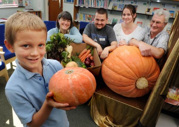 JPCT 071014 S14420547x Horsham. Northholmes school. Nathan, watched by teacher and family, holds a small pumpkin with the giant one behind -photo by Steve Cobb SUS-140710-143544001