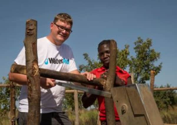 Adam Green collects water at the clean water source in Bobol village, Uganda, during a humanitarian trip
