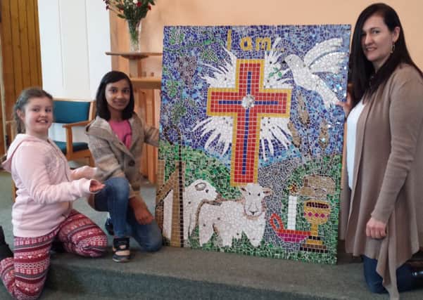 Youngsters Rosie and Komal pose with London Road Methodist Church's mosaic with artist Fiona Nethercleft