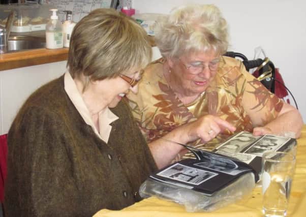Ester and Pam looking back at pictures of Pam's family from 1965, the year Contact the Elderly began