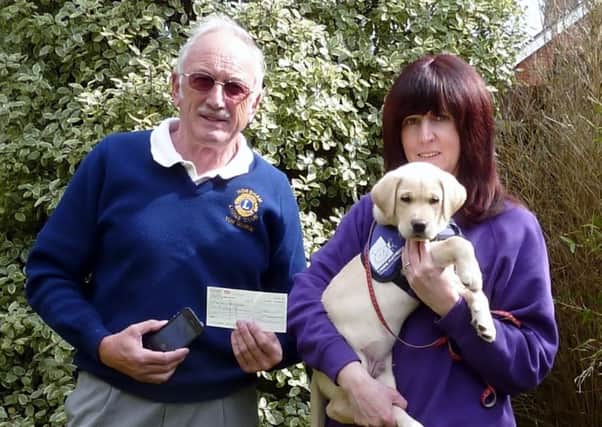 Horsham Lions Club Services Chairman Tom George presents Jane Bullen, a volunteer puppy parent for Canine Partners and her puppy Tetley, with the generous cheque SUS-150421-112035001