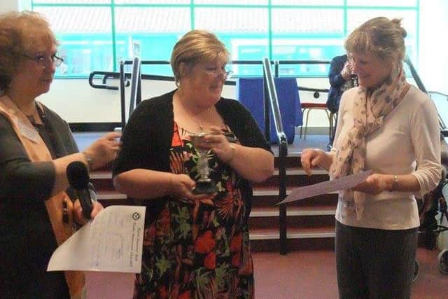 Cygnets leader Jackie Freeman accepts the trophy from national chairman Julie Cotton, watched by organiser Carolyn Harvey