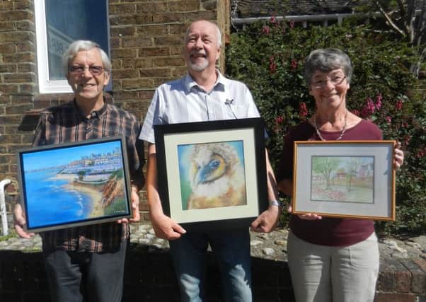 John Stenning, Mark Juby and Eve Wilson each holds one of their paintings for the exhibition