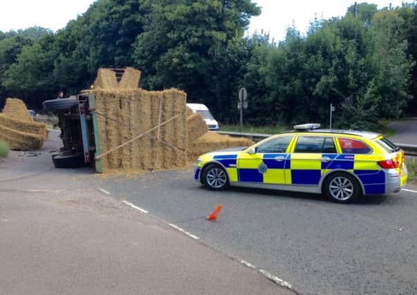 An overturned trailer carrying hay bales is causing havoc on the A24