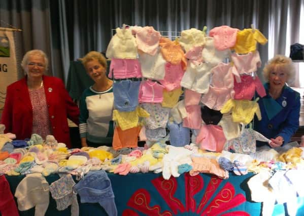 Ferring WI chairman Toni Rose and member Liz Hunter, left, show West Sussex Federation chairman June Moran the knitted goods