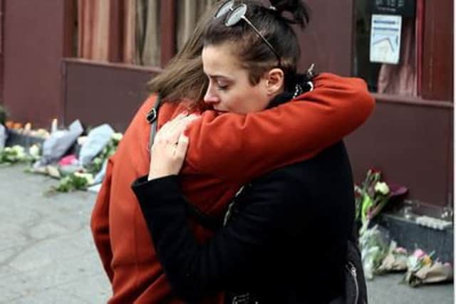 Two women embrace outside the Le Carillon bar after laying flowers in tribute to those killed. SUS-151114-133204001