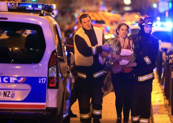 A woman is helped by the emergency services during the attacks in Paris whi has left at least 129 people dead