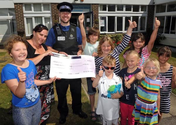 Tarring PCSO Ben Cruise in 2014 handing a cheque Thomas ABecket Infant School in 2014