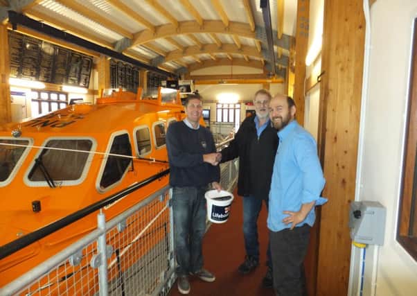 Shoreham lifeboat coxswain Steve Smith, left, accepts the money from Robin Upton, centre, and Mark Ford