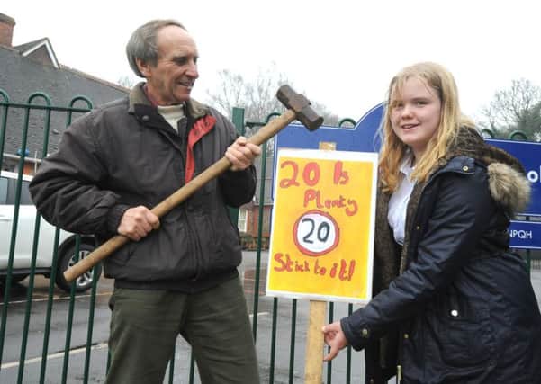 Eddie Lintott putting up a new speeding sign with the artist, Tabitha Hay-Parker, 11, outside Stedham Primary School