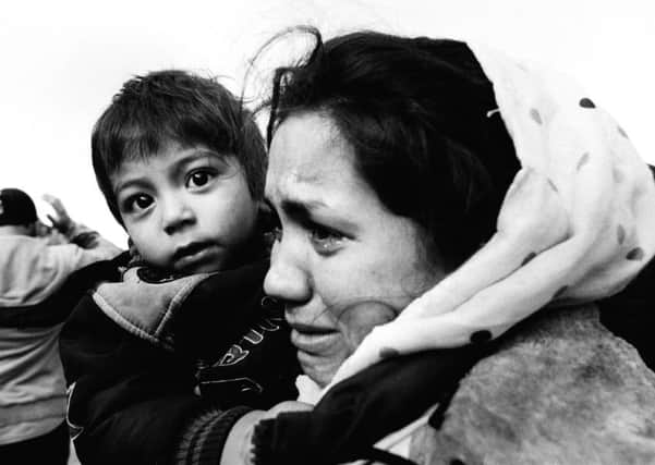 An Afghan mother cries with relief as she clasps her child. Photo by Giles Duley
