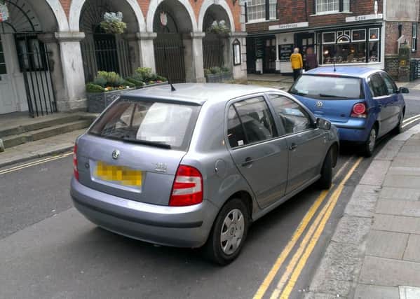 Two cars parked on double yellow lines outside the town hall