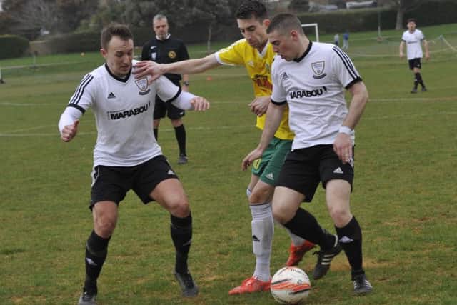 Bexhill United duo Gordon Cuddington and Jacob Shelton tussle for possession with Sidlesham forward John Phillips. Picture by Simon Newstead (SUS-160326-214627002)