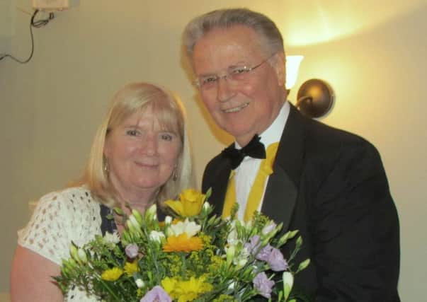 President-elect John Bayley presents a bouquet of flowers to current president Sue Virgo