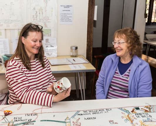 Tina Greene (right) presents Philippa Whitehillwith a coffee mug, sitting in front of the Battle Community Tapestry.

Photograph by Peter T Greene. SUS-161205-130814001