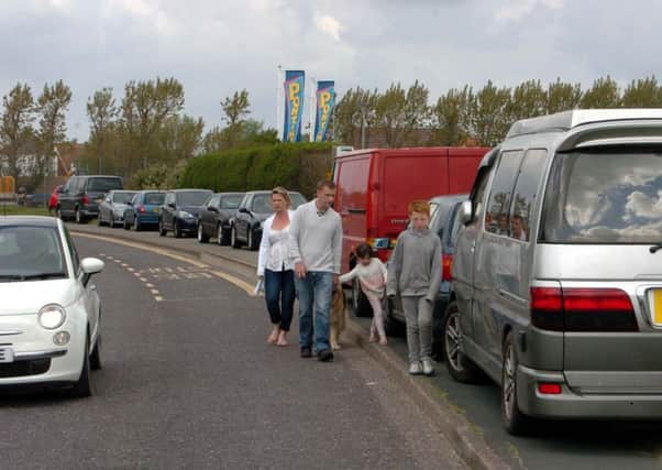 Familes walking in the road to get past cars parked on the pavement in Camber. Photo by Alan Jones
