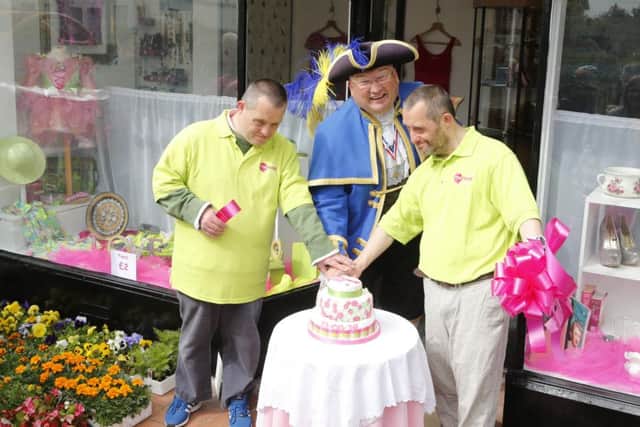 Town crier Bob Smytherman cuts the cake with Mencap volunteers. Photo by Eddie Mitchell.