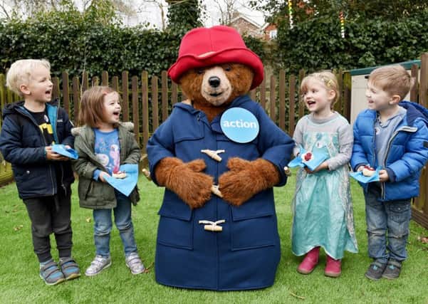 Action Medical Researchs mascot Paddington Bear TM enjoying a tasty cream tea with some young friends