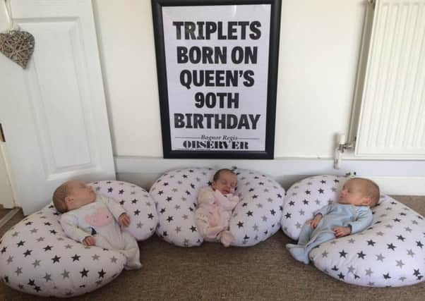 Triplets (from L to R) Polly, Penny and William together, with an Observer bill in their room which marked their birth on the same day the Queen turned 90
