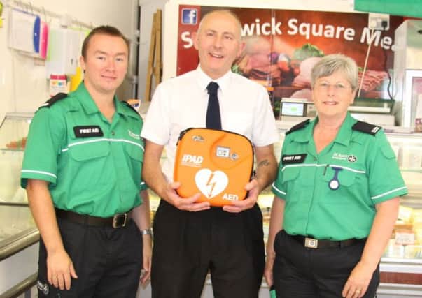St John Ambulance volunteer Carl Bennett, John Burtenshaw and volunteer Elizabeth Burchell with the defibrillator being installed at Southwick Square Meat Ltd