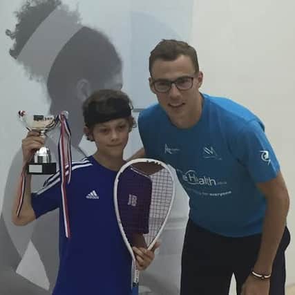 Jonah Bryant holds his under-11 national title alongside squash professional Nick Matthew