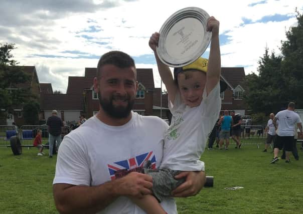 St Leonards strongman Aaron Davis and son Riley proudly clutching his prize