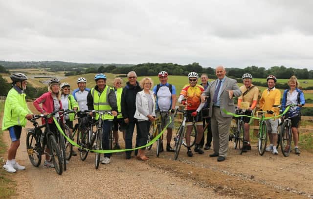Cllr Keith Glazier cuts the ribbon to officially open the new Greenways alongside Combe Valley Way (Bexhill-Hastings Link Road), watched by representatives from local cycling groups SUS-160729-140109001
