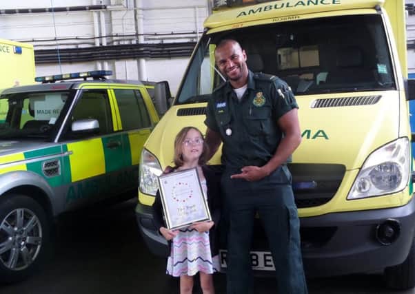 Eight-year-old Maia Bryant with paramedic Phil Ibrahim and her award after helping save her great-grandfather. Photo by SECAmb SUS-161208-102500001