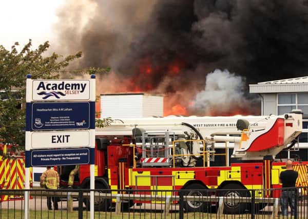 Smokes billows from a fire at Selsey Academy as three firefighters attack the blaze. Picture by Chris Hatton