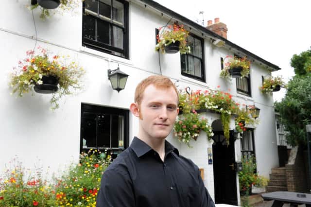 Arran Collis, son of pub landlord Michael Collis outside the Spotted Cow pub in Angmering by the empty frame which held the pub sign